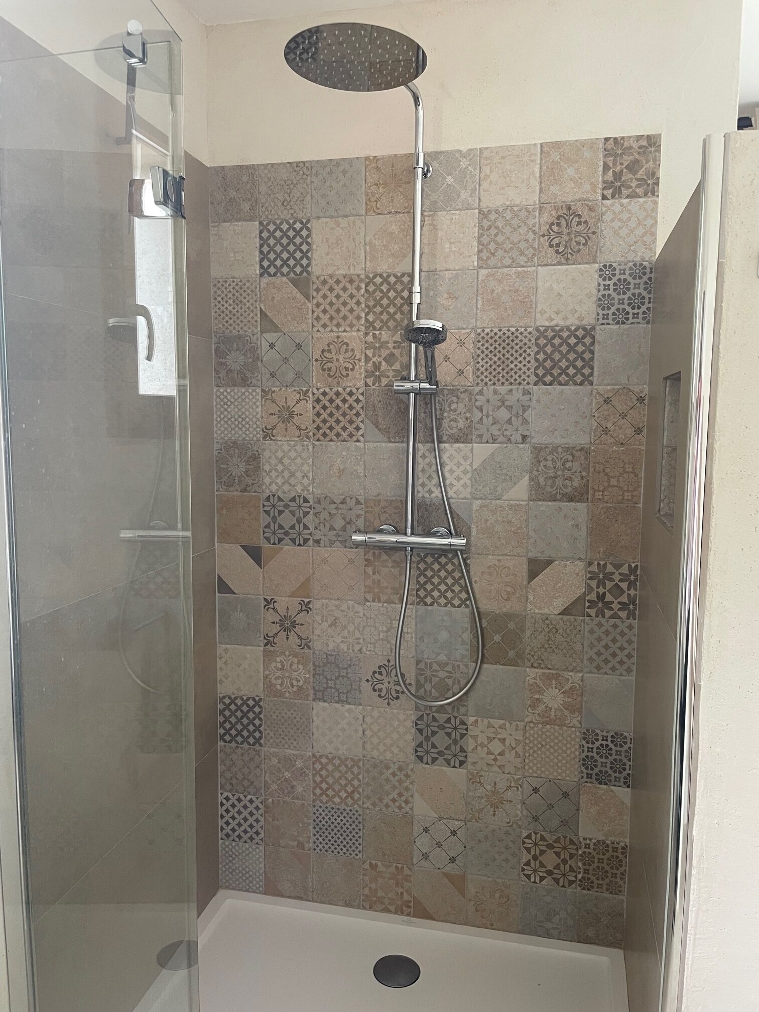 A glass-enclosed shower stall with a handheld showerhead and a wall-mounted rain showerhead.