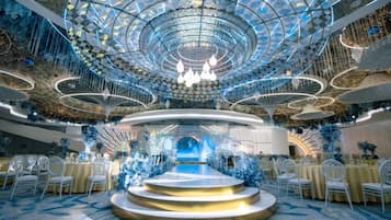 A grand hall with a central stage, tiered seating, and a decorative ceiling.