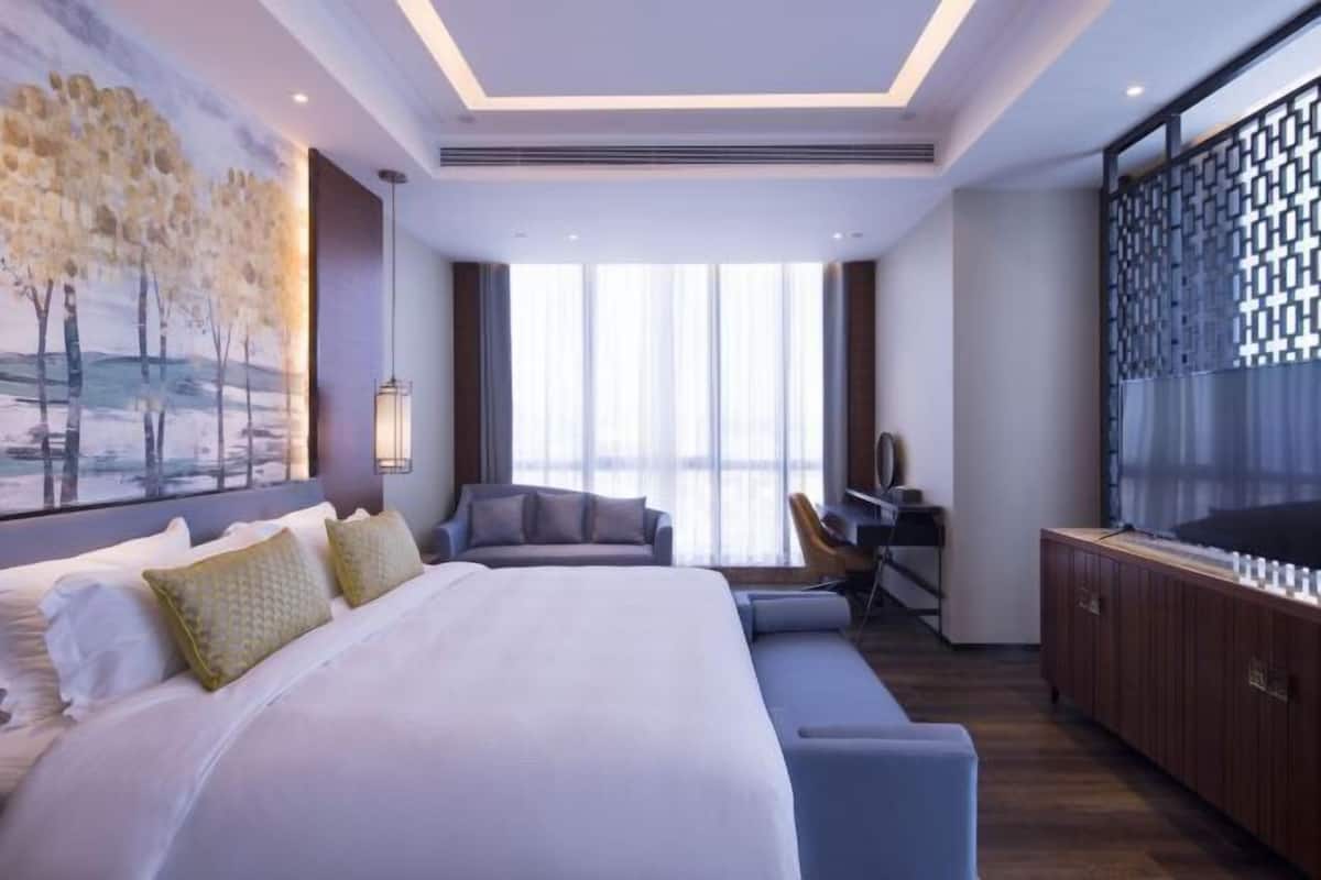 Une chambre d’hôtel moderne équipée d’un grand lit, d’un bureau, d’une chaise et d’un téléviseur.