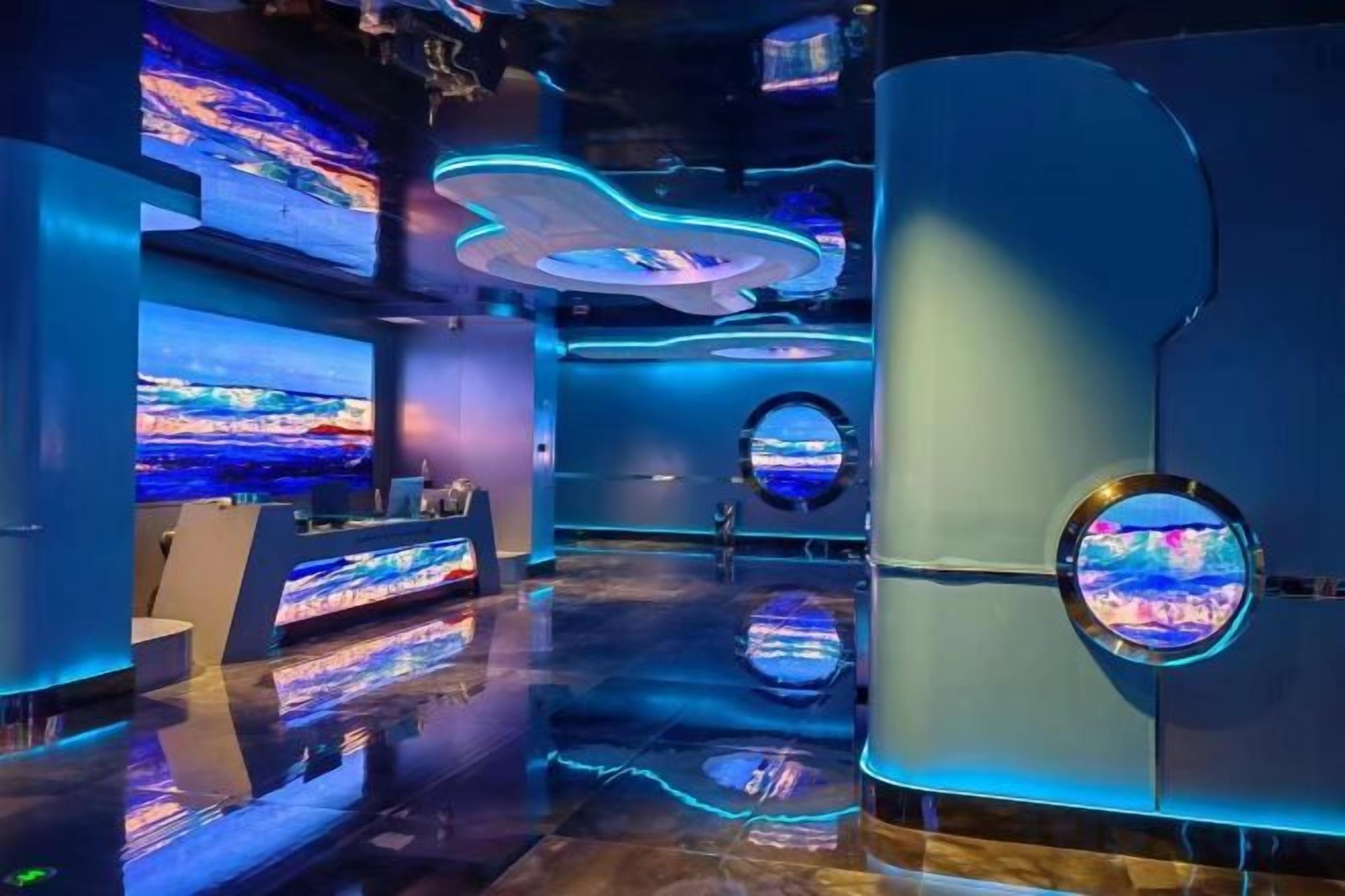 Ein modernes Interieur mit einer Rezeption, großen digitalen Bildschirmen und einem spiegelnden Boden.