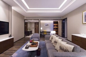 Una sala de estar moderna con una televisión de pantalla plana, un sofá, una mesa de centro y un comedor con una mesa y sillas.