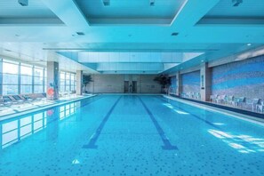 A large indoor swimming pool with clear lanes, a tiled floor, and a view of the city through large windows. - Rong Qiao Hotel (Fuzhou)