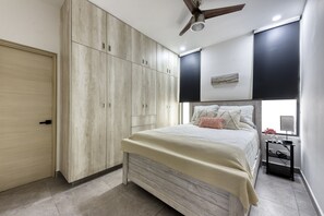 A bedroom with a bed, wardrobe, ceiling fan, and bedside table.