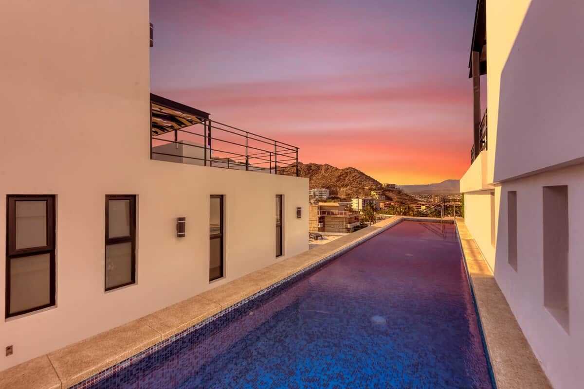 A swimming pool with a view of a sunset and distant mountains.
