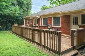 A two-story brick house with a wooden deck and a fenced backyard.
