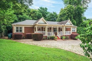 A two-story house with a front porch, brick exterior, and a gravel driveway.
