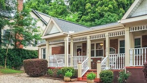 A two-story house with a front porch, a brick chimney, and a number 221 sign.