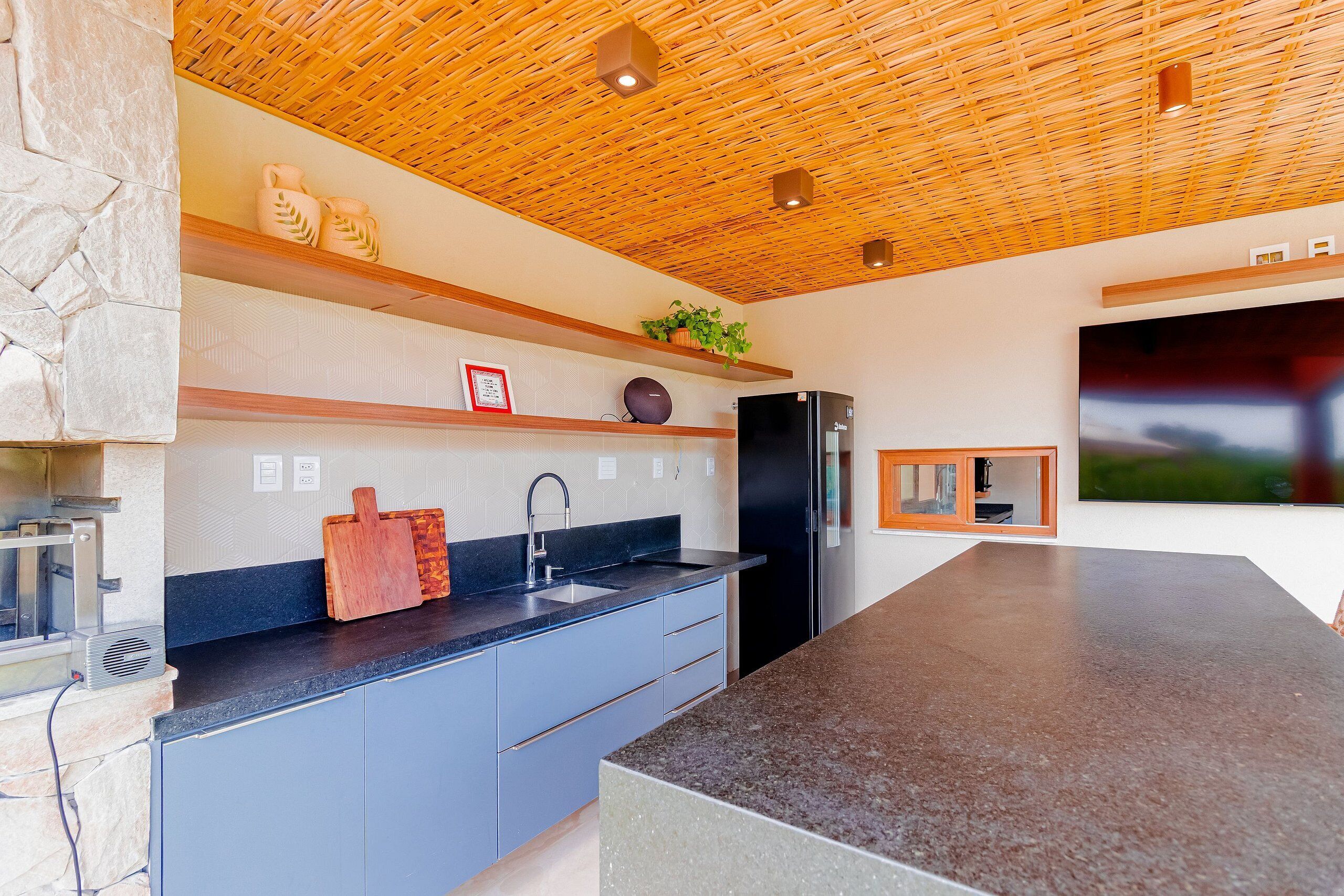 Eine moderne Küche mit einem schwarzen Kühlschrank, einem eingebauten Backofen und einer großen Kochinsel mit dunkler Arbeitsplatte.