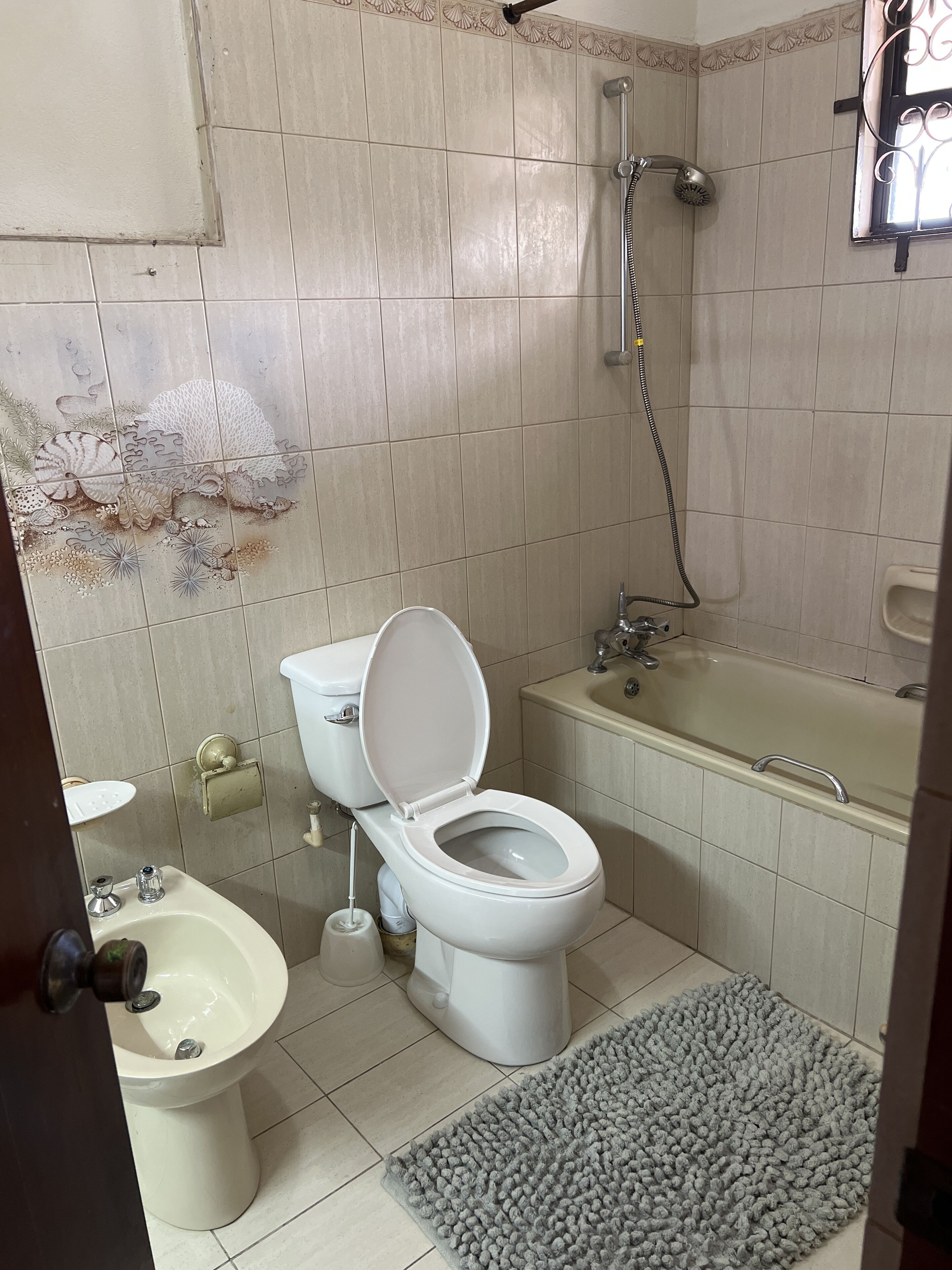 A bathroom with a toilet, bidet, sink, and bathtub.