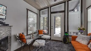 A modern living room with a fireplace, large windows, and a cozy seating area.