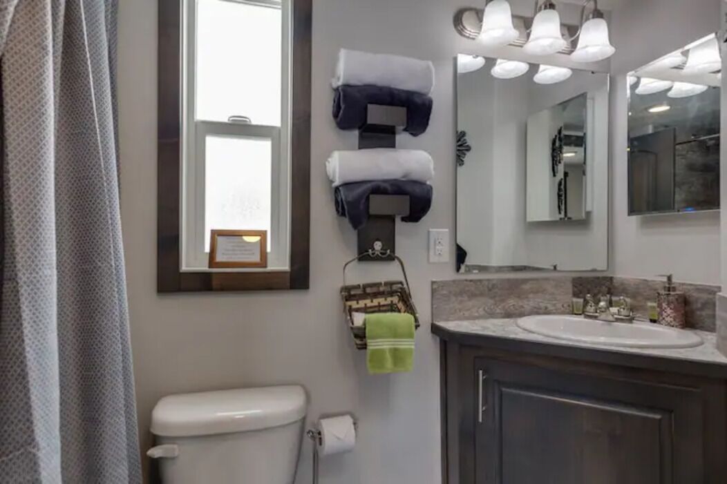 Ein Badezimmer mit Toilette, Waschbecken, Handtuchhalter und Spiegel.