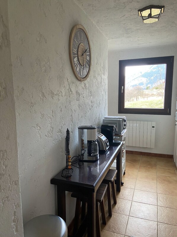 Eine Küche mit einem Holztisch, einer Kaffeemaschine, einem Toaster und einem Fenster mit Bergblick.