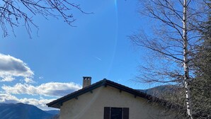 Yhden kerroksen talo, jossa on savupiippu, kaksi ikkunaa ja pieni patio.