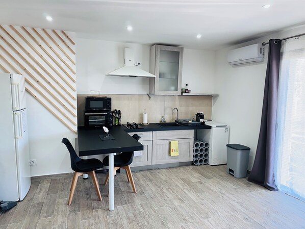 Een koelkast, een oven, een kookplaat, kookgerei, borden en bestek