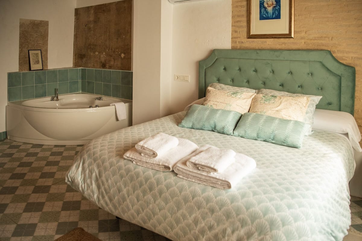 Ein Hotelzimmer mit einem Bett, einer großen Badewanne und einem Schachbrettmuster Boden.