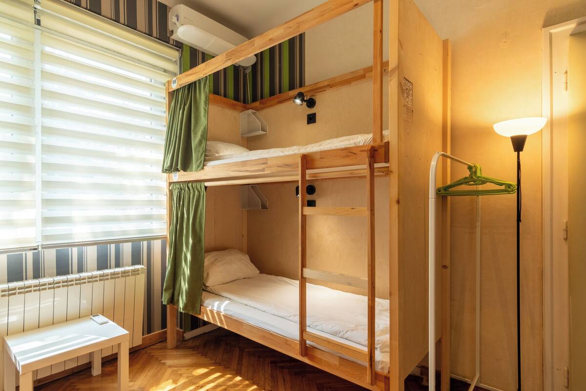 A bunk bed room with a radiator, a bench, and a hanging light fixture.