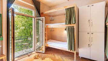 Une chambre avec des lits superposés, une armoire et une porte-fenêtre coulissante donnant sur un espace extérieur équipé d’une chaise.