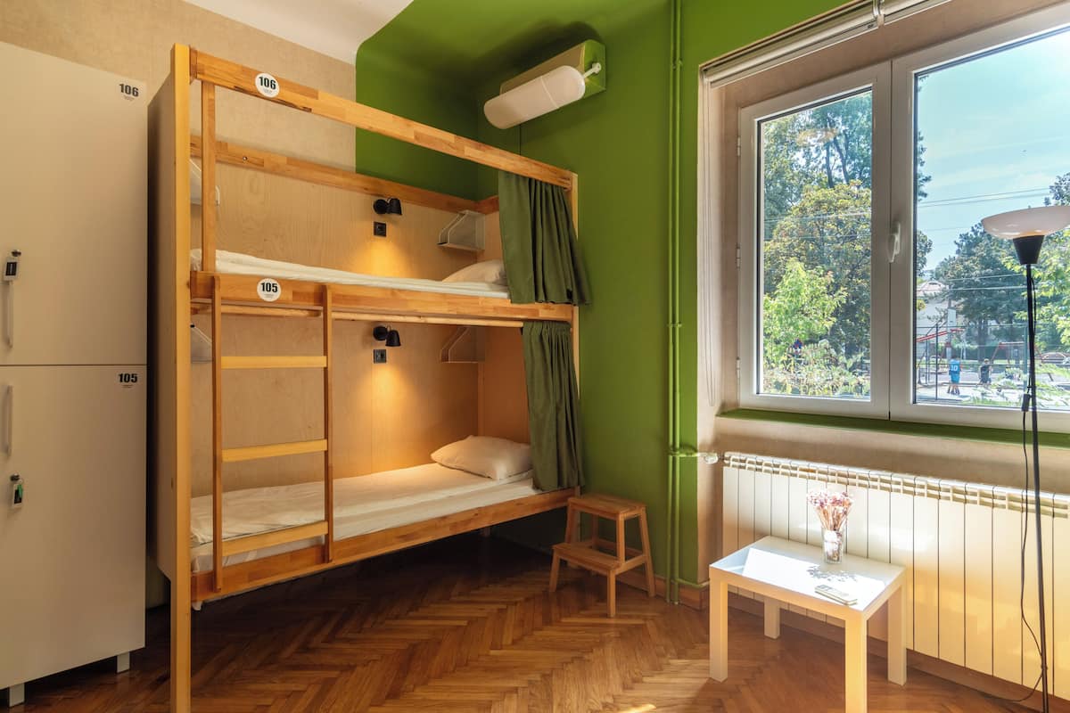 A bunk bed room with a small table and a window with a view of trees.