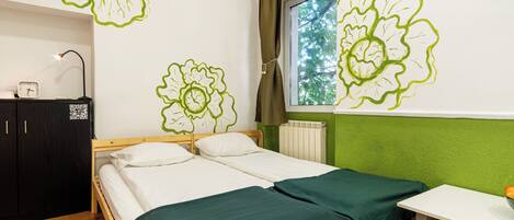 A room with a bed, a desk, a window with curtains, and a radiator.