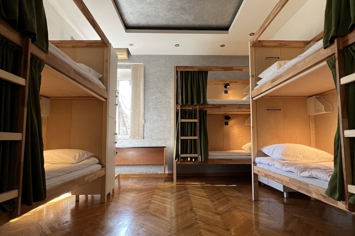 A dormitory room with bunk beds, wooden flooring, and a skylight.