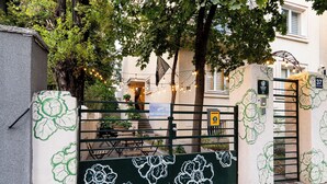 A gated entrance with floral patterns, a building entrance, and a sign indicating a parking area. - Cabbage Hostel (Belgrade)