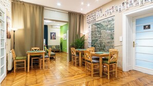 A dining area with wooden furniture and a large window with a view. - Cabbage Hostel (Belgrade)