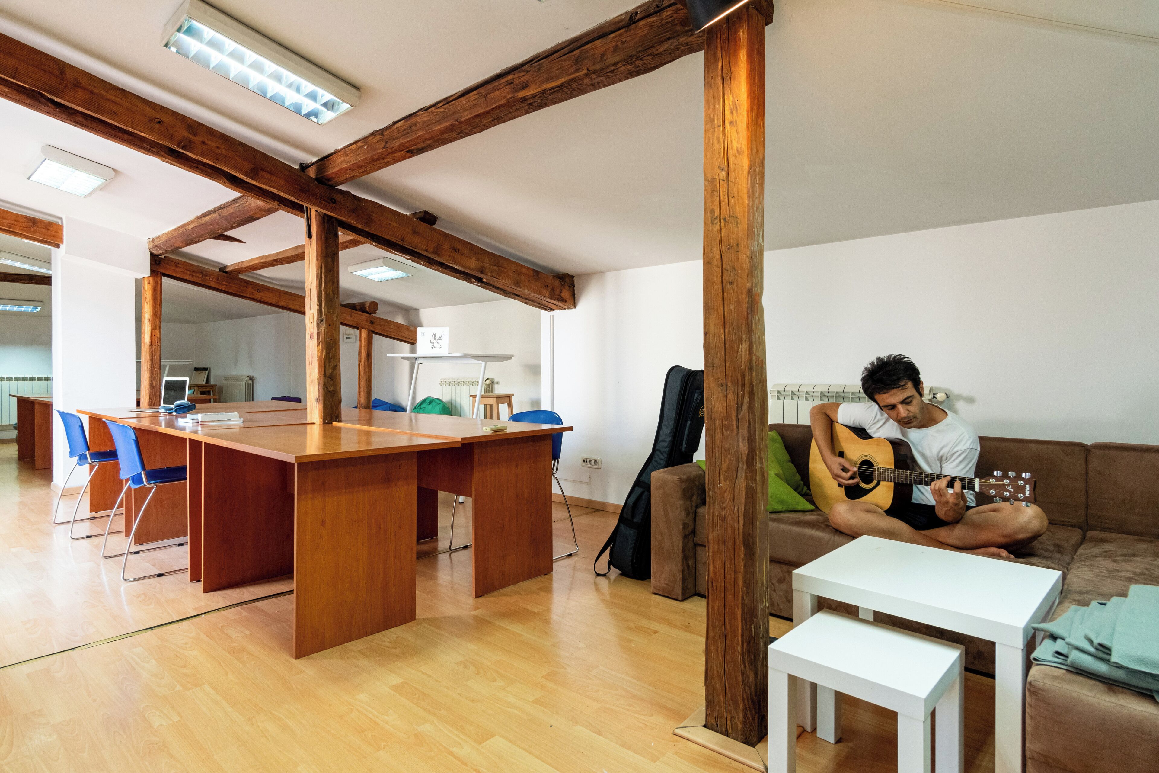 A spacious living area with a wooden dining table, blue chairs, a sofa, and a white coffee table.
