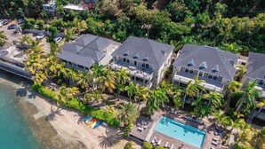 Une propriété située en bord de mer, comprenant plusieurs maisons, une piscine et un espace de plage.
