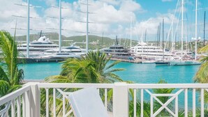 Un port de plaisance où sont amarrés de nombreux yachts, un ciel dégagé et des palmiers.
