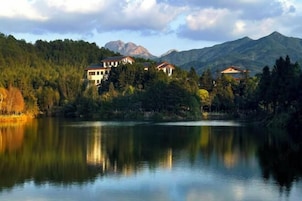 Una propiedad junto al lago con varias edificaciones rodeada de bosque y montañas.