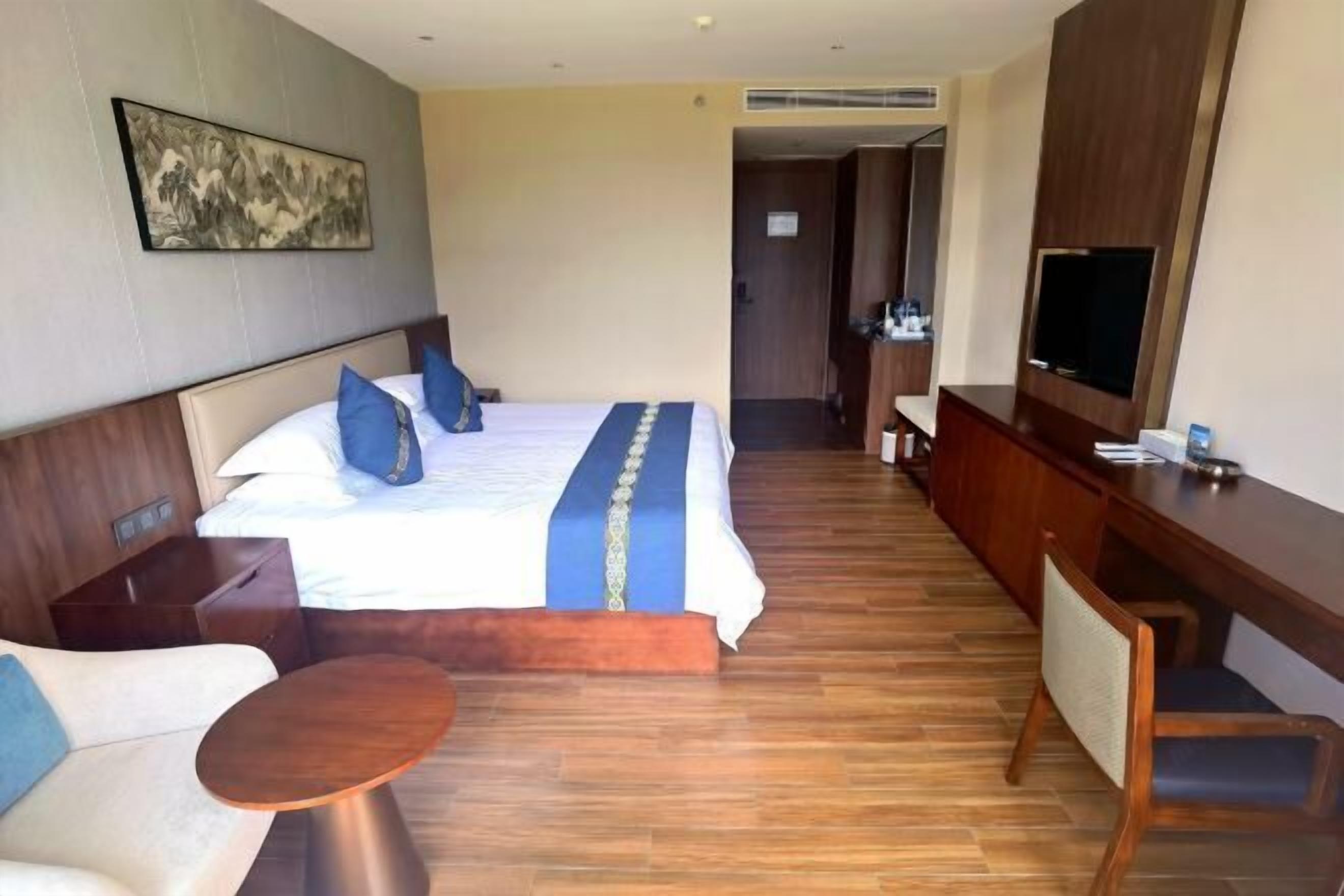 Una habitación de hotel con una cama, un escritorio, una silla, una mesita y un televisor.