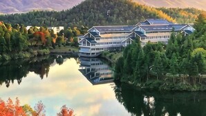 Un hôtel situé au bord d’un lac, dont l’image se reflète dans l’eau, entouré d’arbres et de montagnes.