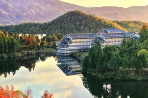Un hotel junto al lago, reflejado en el agua, rodeado de árboles y montañas.