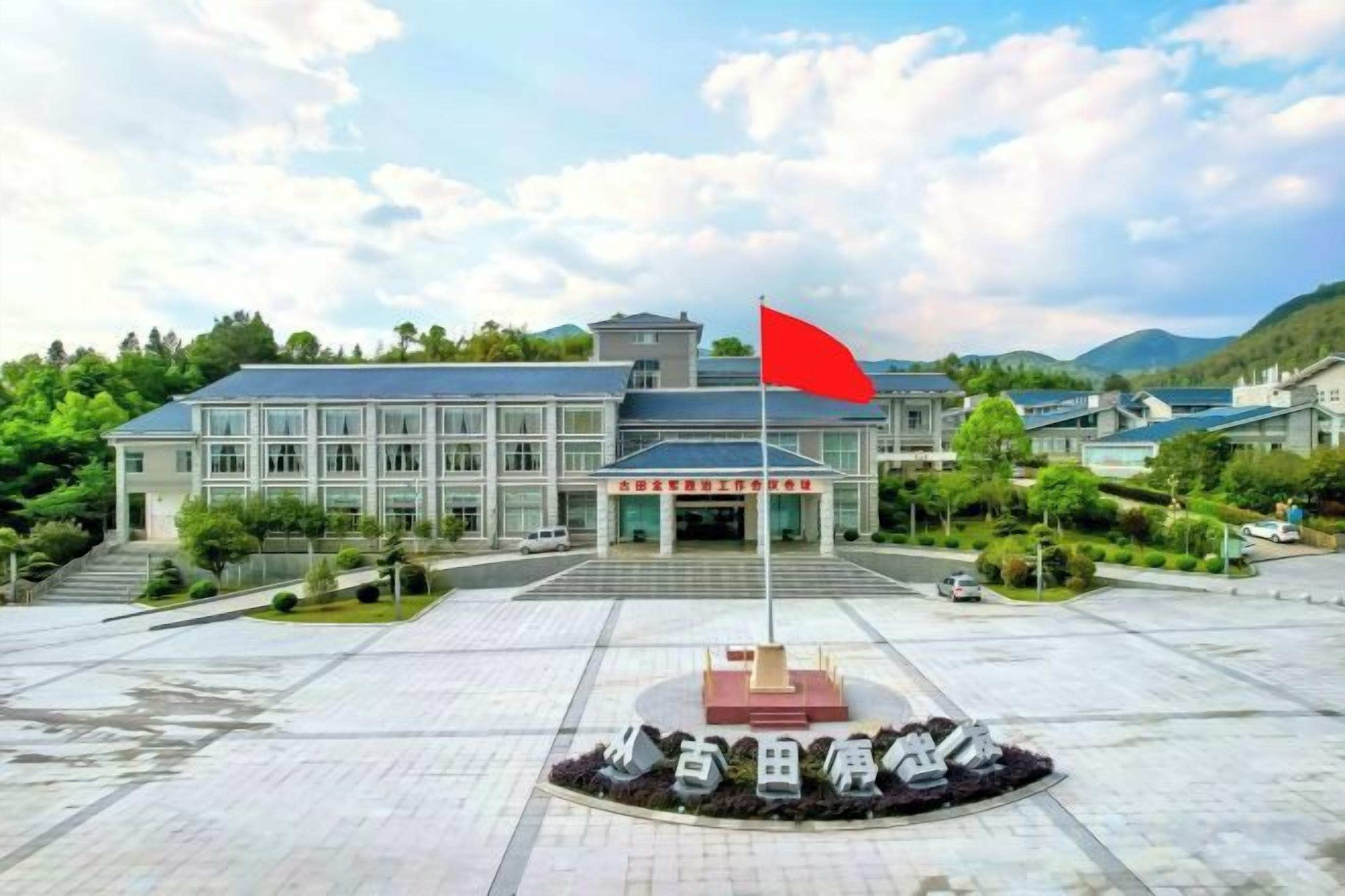 A building with a flagpole, a paved entrance area, and a landscaped garden.