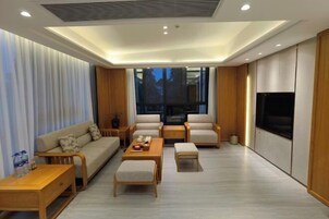 Una sala de estar moderna con un sofá, dos sillones, una mesa de centro y un televisor.