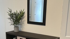 Une console en bois foncé dotée de tiroirs de rangement, une plante en pot et un miroir accroché au mur.