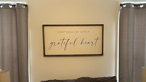 Un cadre contenant une citation inspirante accroché au mur, un canapé marron foncé avec un coussin à rayures, et deux lampes de chaque côté.