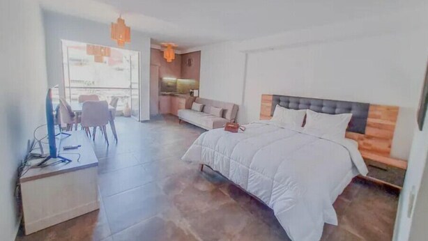 A modern bedroom with a large bed, a desk with a computer, a sofa, and a dining area. - Cozy studio with balcony (Marrakesh)