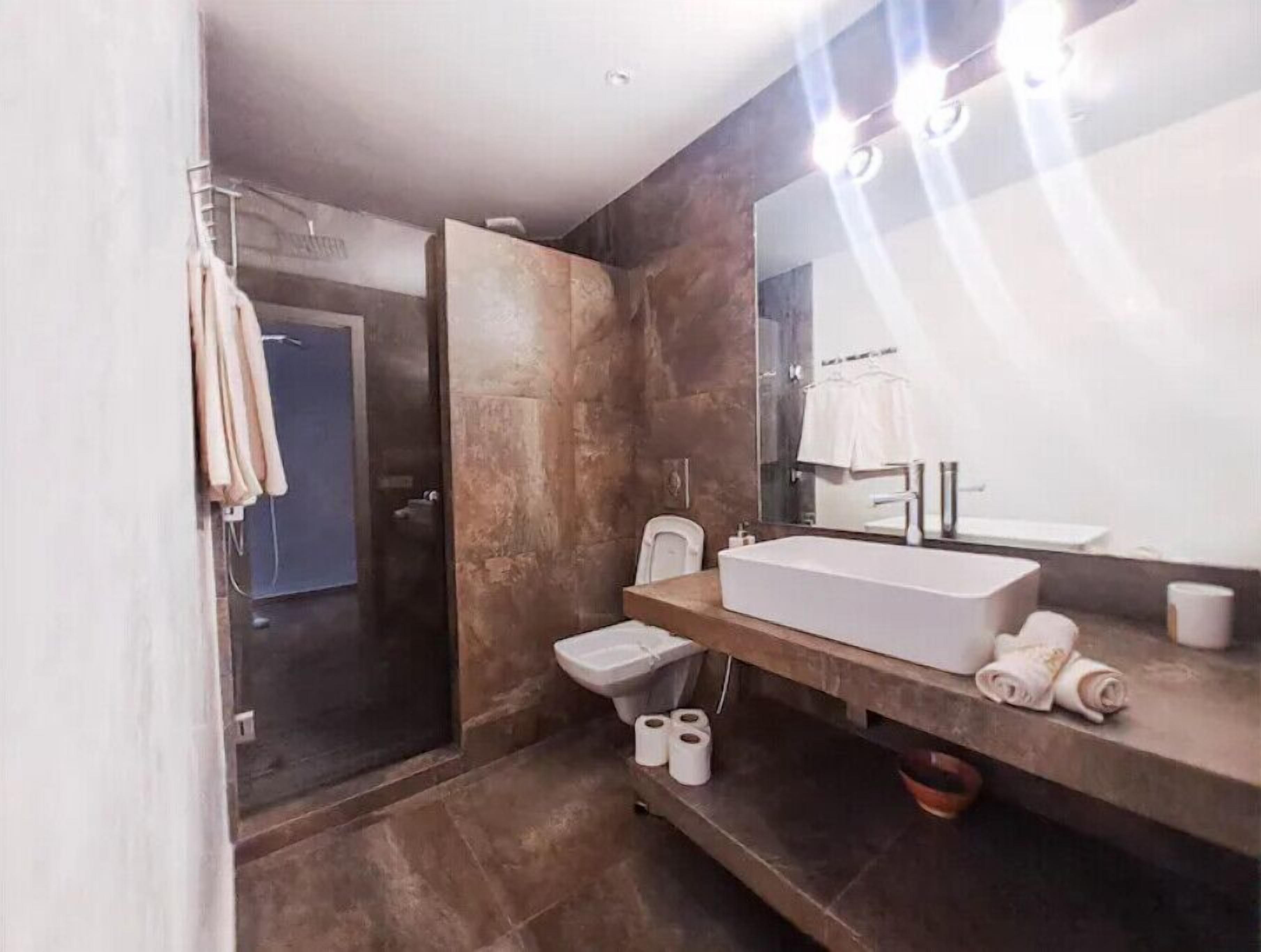 Un baño moderno con un espejo grande, una bañera, un inodoro y una zona de ducha.
