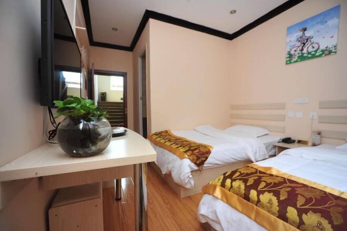 Habitación de hotel con dos camas, un escritorio con un florero, un espejo y un cuadro en la pared.