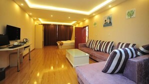 A modern living room with a sofa, a coffee table, a TV, and a dining area.