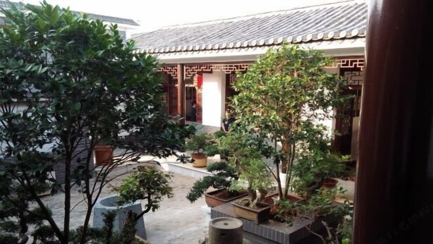 A traditional courtyard with potted plants and a stone water feature.