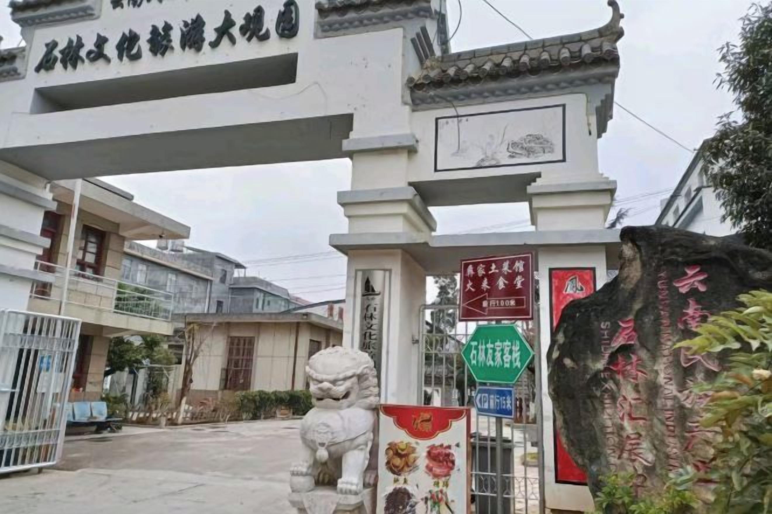 Een traditionele Chinese poort met een stenen leeuwenbeeld bij de ingang.