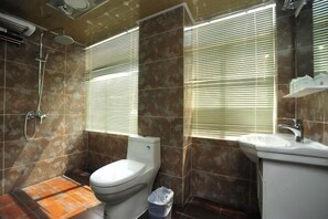 A bathroom with a toilet, shower, and sink.