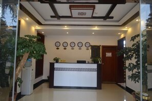A reception area with a reception desk, wall-mounted clocks, and potted plants. - Youjia Inn (Shilin)