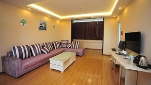 A modern living room with a sectional sofa, a coffee table, a flat-screen TV, and a desk with a computer.