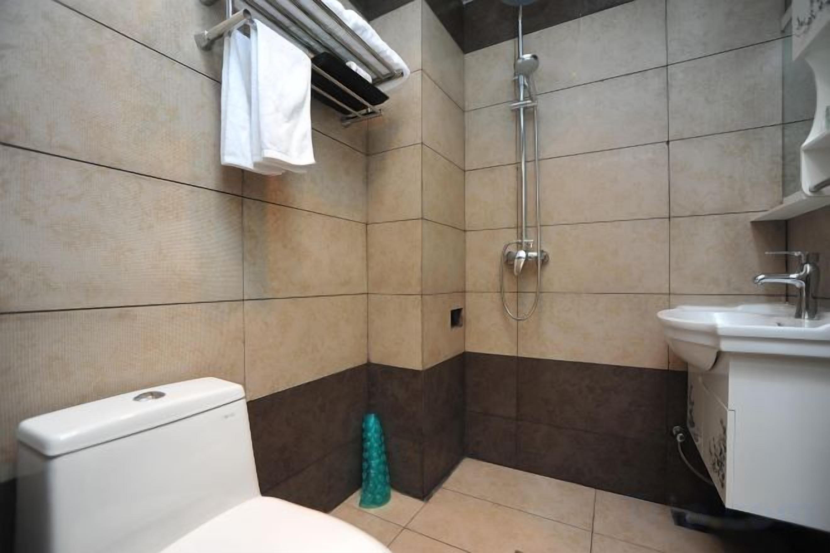 A bathroom with a toilet, shower, and sink.