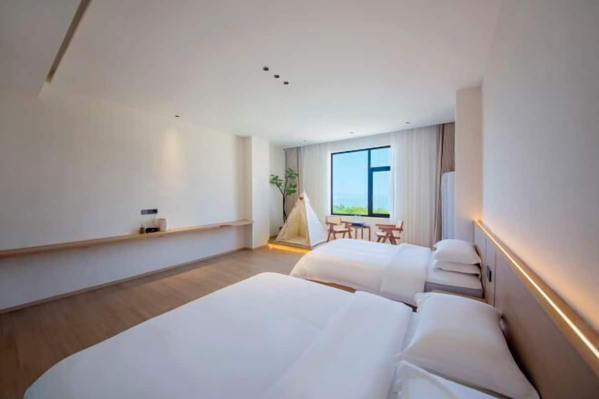 A modern hotel room with two beds, a large window, a small table, and a tent-like structure.