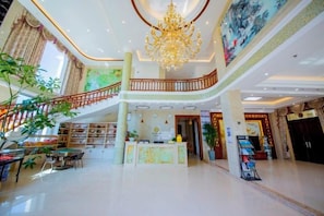 Un'ampia hall con un lampadario, una scala e la reception.