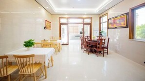 A dining area with a white table, wooden chairs, and a potted plant. - Lanting Holiday Villa (Putian)